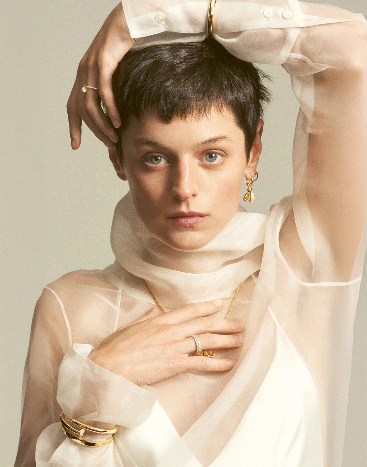Photo of Emma Corrin wearing the Juste un Clou medium bracelet and ring, the Baignoire bangle watch, the Grain de Café earring and necklace, and the Broderie de Cartier ring