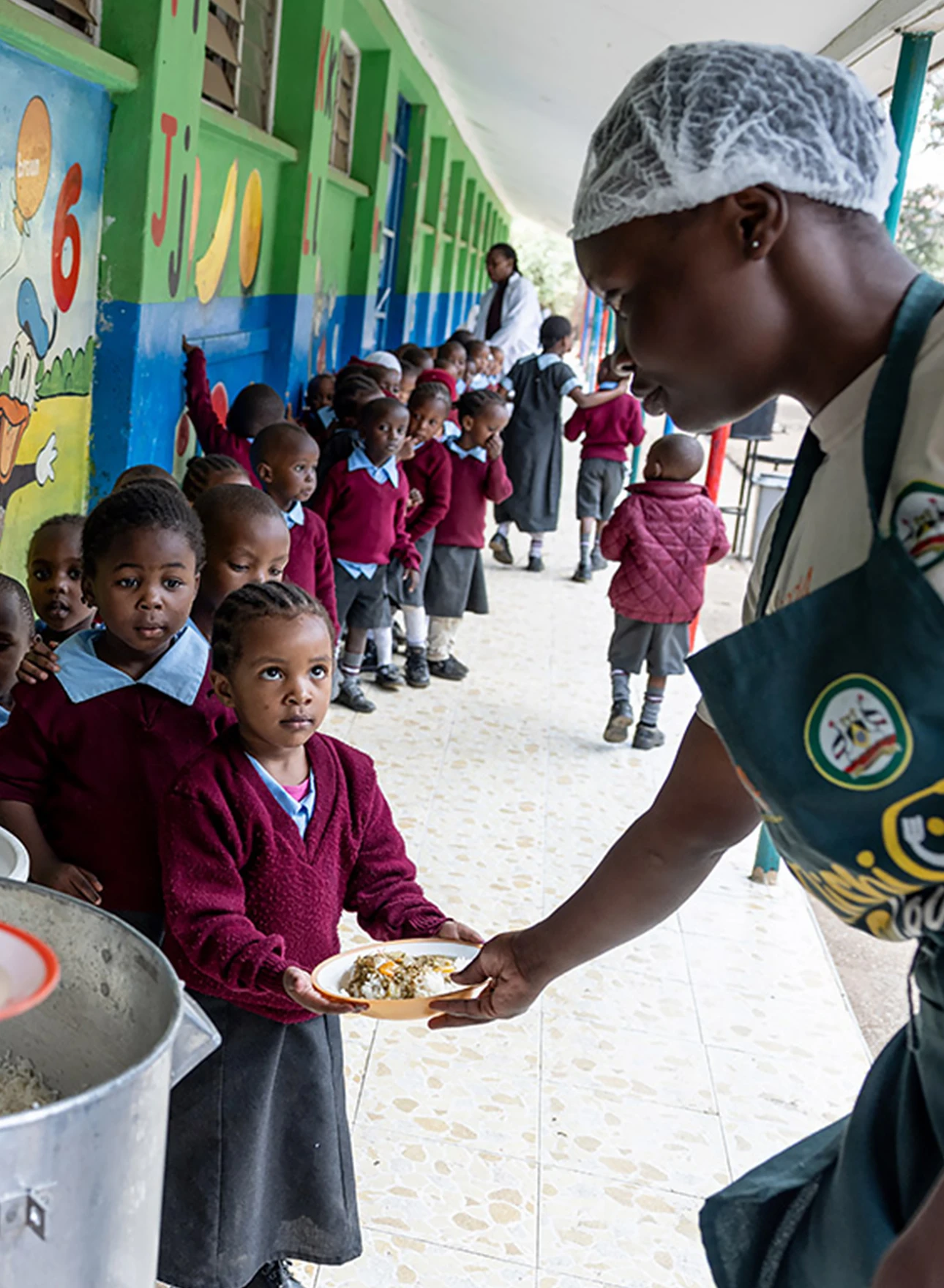 Photo of  woman handing over a plate of food to a child